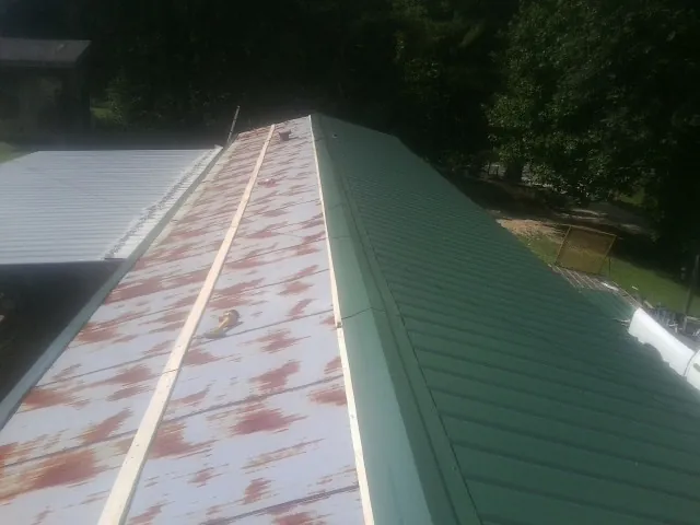 Old rusted panels beside newly installed green metal roofing — Wind Damage Roof Repair by Roofing Brothers in Saint Clair Shores