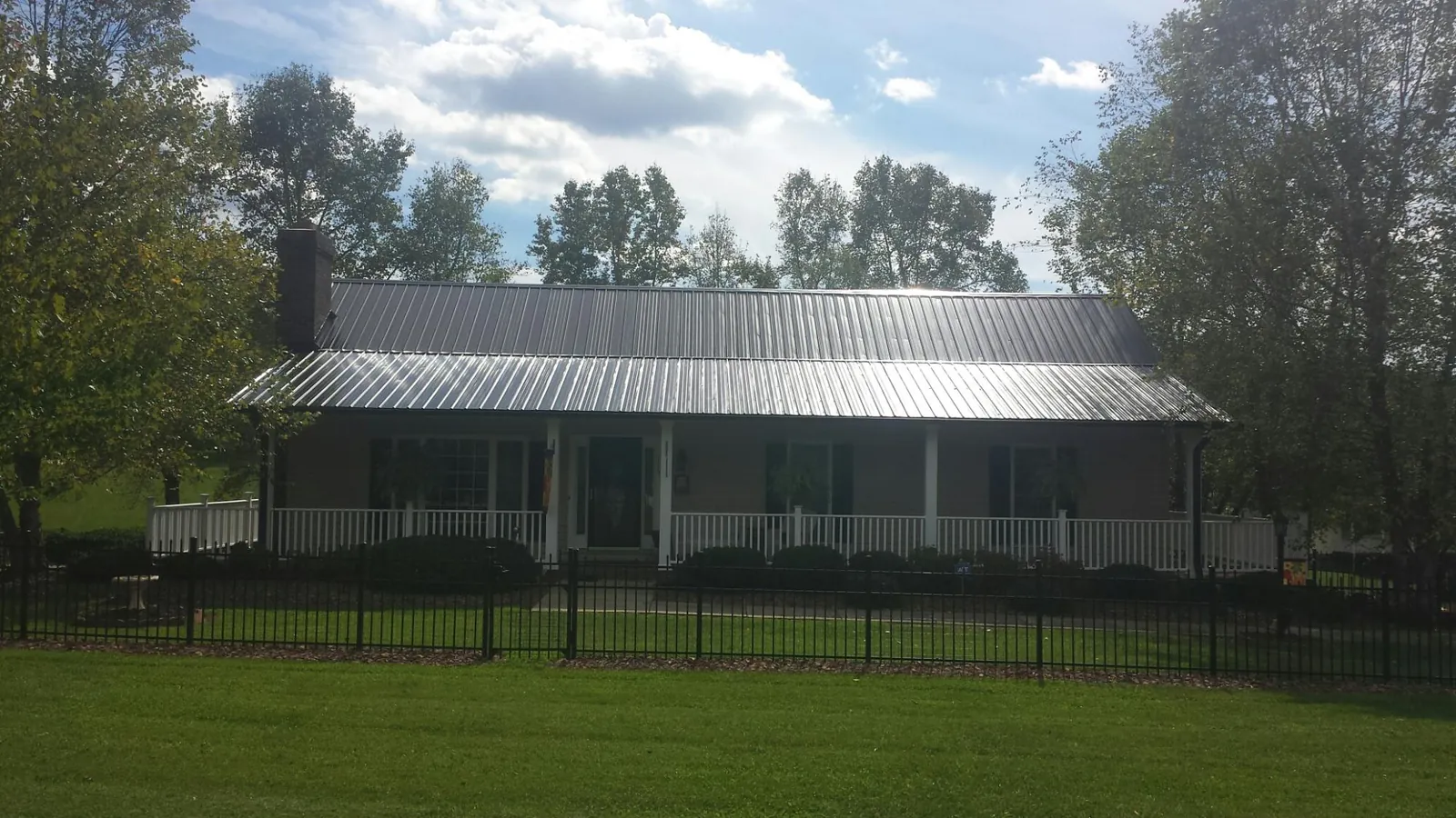 Gray metal roof on a brick ranch with a full width front porch — Gutter Guard Installation work by our crew in Saint Clair Shores