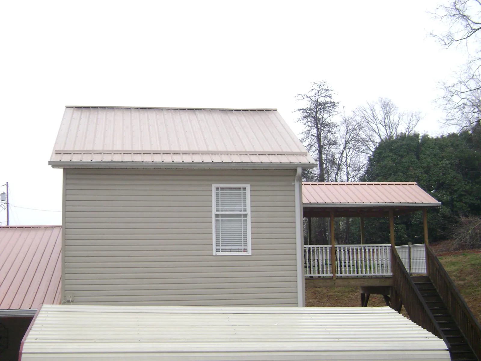 Tan metal roofs on a two story addition and attached porch, from a Roof Replacement job in Saint Clair Shores
