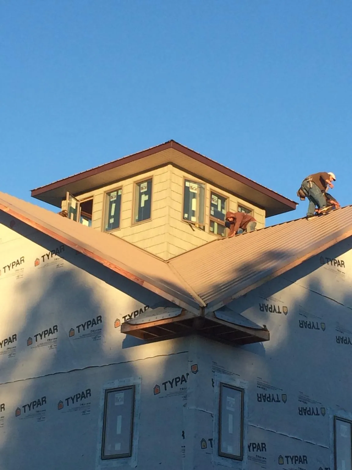 Roofers working around a rooftop cupola on a new metal roof at sunset — Roof Waterproofing in Saint Clair Shores by Roofing Brothers